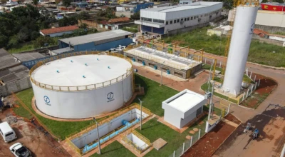 A imagem mostra uma estação de tratamento de água da Saneago em Aparecida de Goiânia. O local possui grandes reservatórios, estruturas técnicas e áreas verdes, cercado por um bairro urbano com comércios e residências ao fundo.