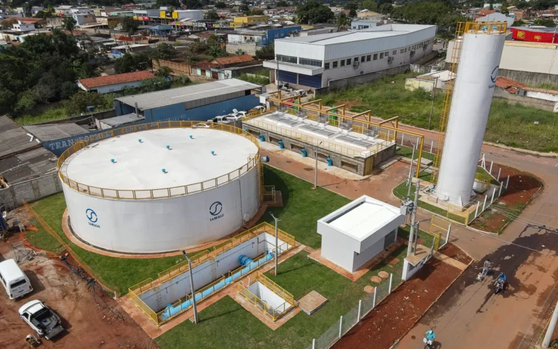 A imagem mostra uma estação de tratamento de água da Saneago em Aparecida de Goiânia. O local possui grandes reservatórios, estruturas técnicas e áreas verdes, cercado por um bairro urbano com comércios e residências ao fundo.