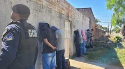 Agentes da GCM e PM abordam grupo durante operação em Aparecida; pessoas encostadas em muro são revistadas em ação de fiscalização.