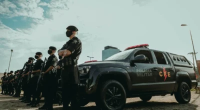 Policiais da CPE estão perfilados ao lado de uma viatura