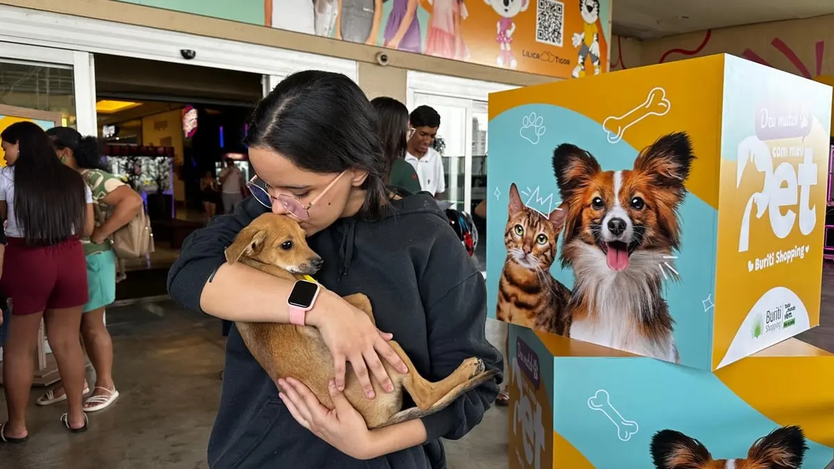Jovem abraça filhote de cachorro durante a Feira de Adoção Responsável.