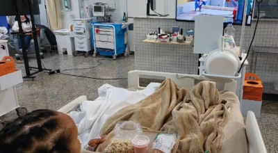 Paciente da UTI do HMAP assiste a desenho animado em uma TV instalada no leito, enquanto faz um lanche.