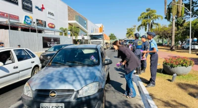 Agentes da GCM e integrantes da Guarda Mirim entregam panfletos a motoristas durante blitz educativa do Agosto Lilás.