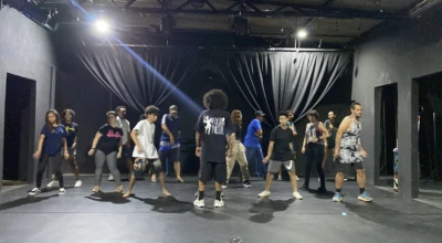 Um grupo de pessoas ensaiando uma coreografia no palco do pontão de cultura da cidade livre.