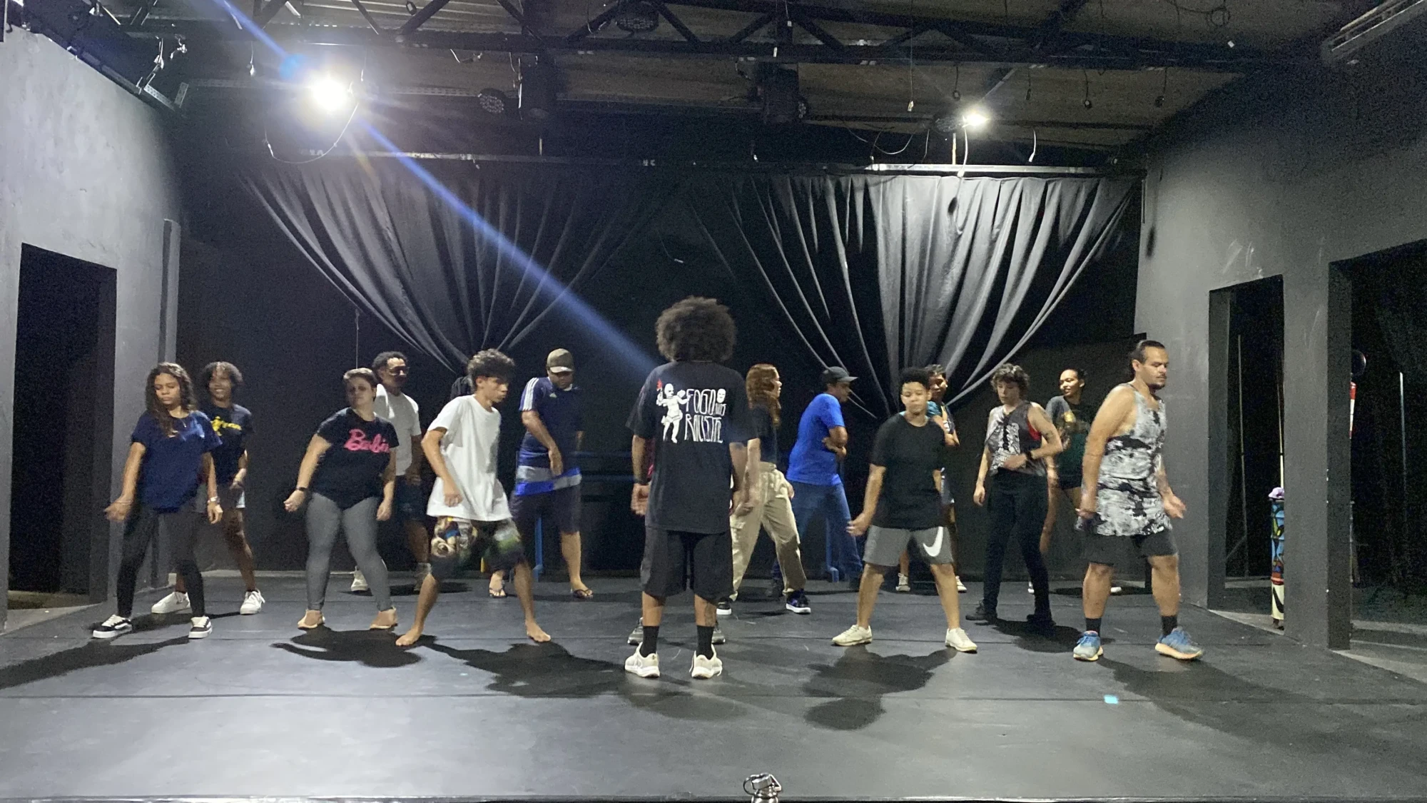 Um grupo de pessoas ensaiando uma coreografia no palco do pontão de cultura da cidade livre.