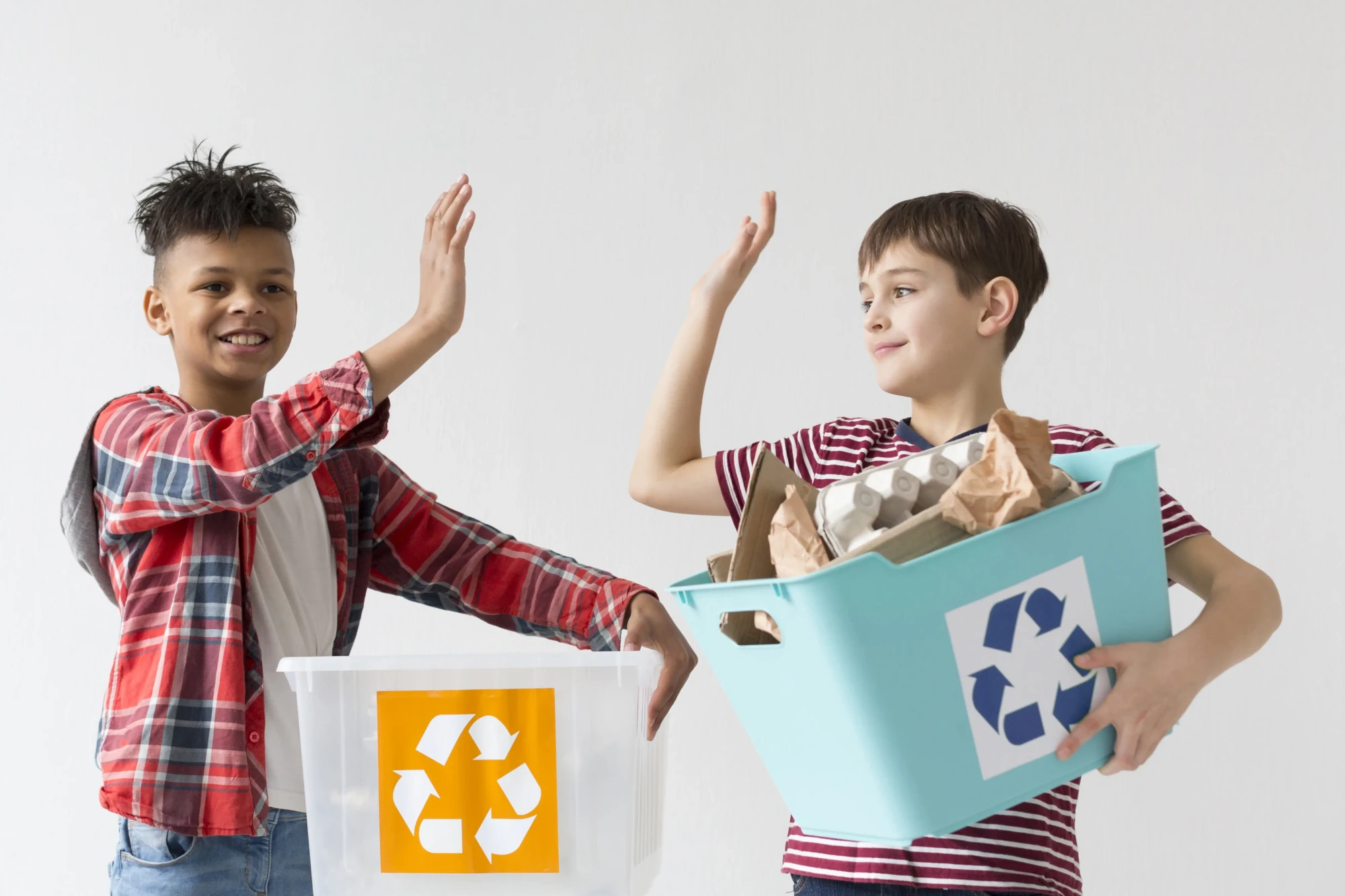 Crianças segurando uma caixa com o símbolo da reciclagem.