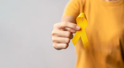 Foto de uma pessoa com camisa amarela segurando um laço amarelo, símbolo do Setembro Amarelo e da prevenção ao suicídio.
