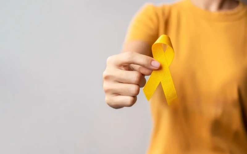 Foto de uma pessoa com camisa amarela segurando um laço amarelo, símbolo do Setembro Amarelo e da prevenção ao suicídio.