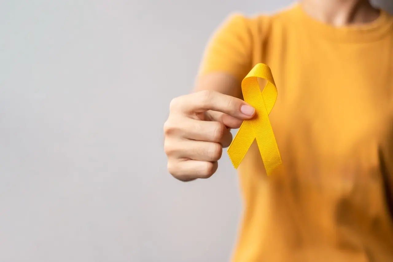 Foto de uma pessoa com camisa amarela segurando um laço amarelo, símbolo do Setembro Amarelo e da prevenção ao suicídio.