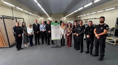 Grupo com policiais penais e autoridades posa em oficina, ao lado de placa do Governo de Goiás.