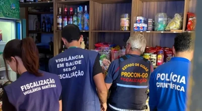 Equipe de fiscalização dentro de um comércio de Aparecida, conferindo prateleiras com bebidas e alimentos. *