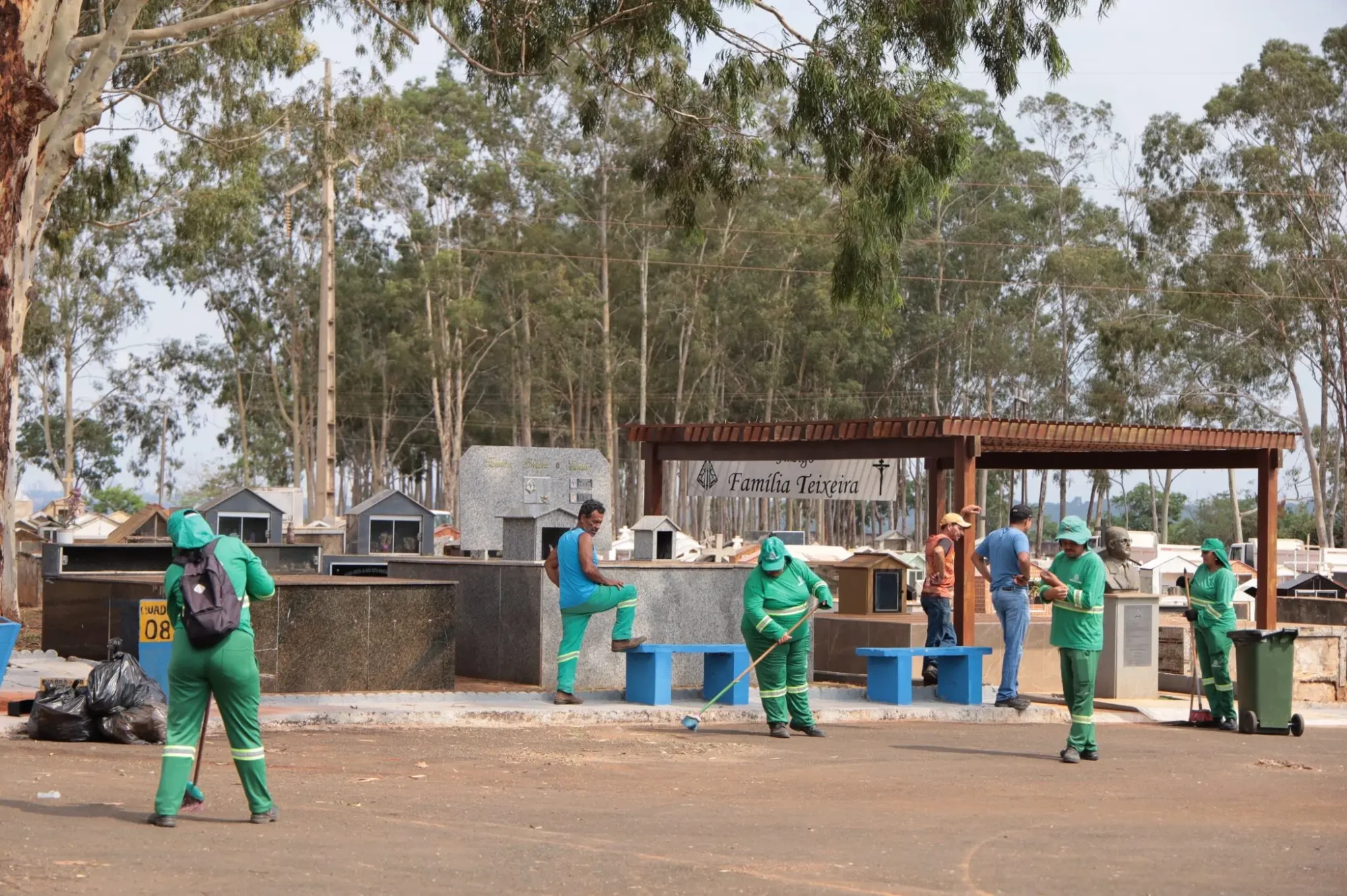 Equipe de limpeza varre e organiza um cemitério.