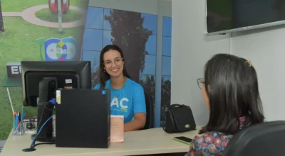 Foto de uma funcionária do SAC atendendo uma pessoa.