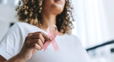 Imagem de uma mulher segurando o símbolo do outubro rosa.