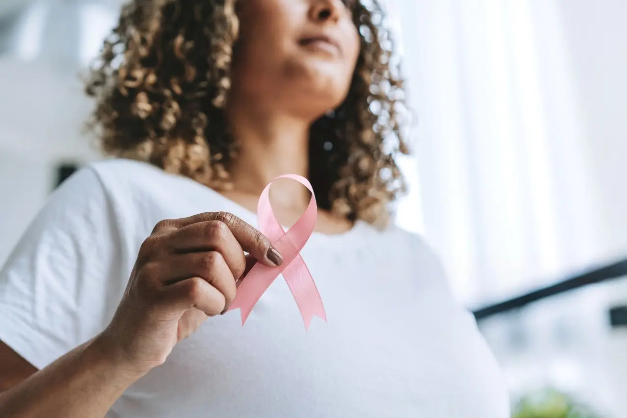 Imagem de uma mulher segurando o símbolo do outubro rosa.