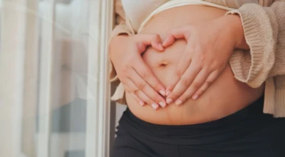 Mulher gestante com as mãos na barriga.