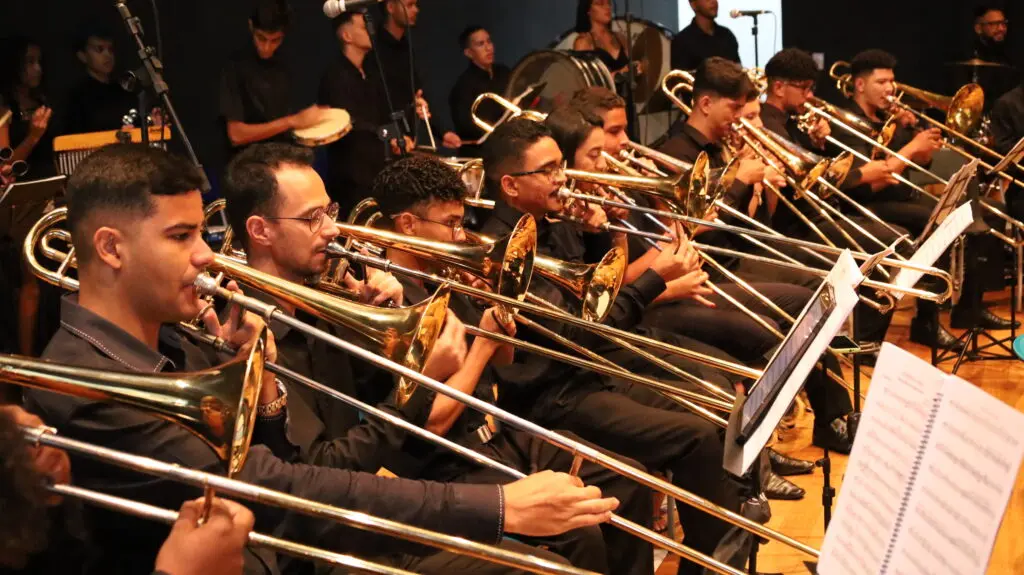 Músicos da banda sinfônica tocam trombones em apresentação