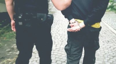 Foto de policial com suspeito algemado.