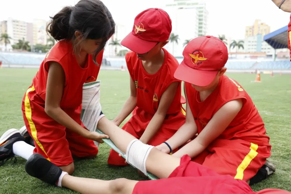 Crianças praticando primeiros socorros.