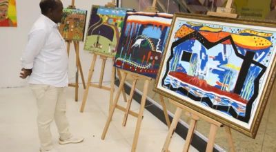 Foto de um homem admirando artes expostas em um salão.