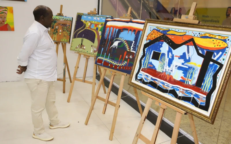 Foto de um homem admirando artes expostas em um salão.