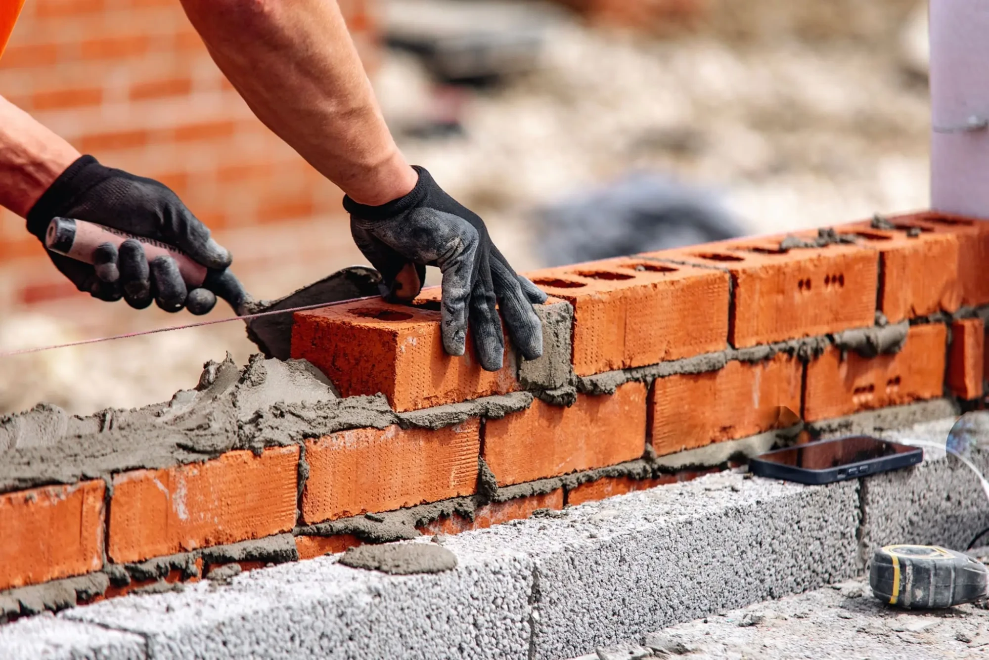 Pedreiro levantando muro em obra.