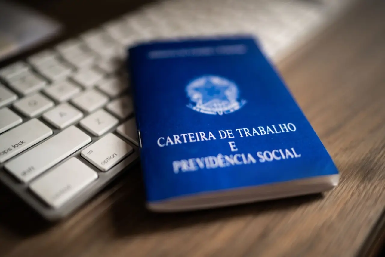 Foto de uma carteira de trabalho perto de um teclado de computador.