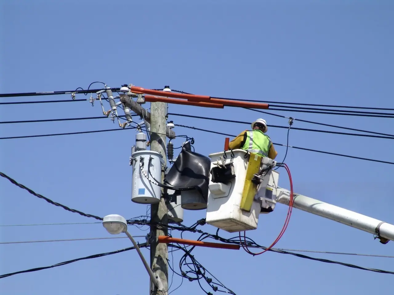 Funcionários de companhia elétrica fazendo manutenção nos fios de energia.