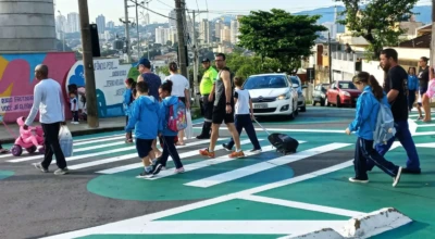 Pais e filhos atravessando a rua em rotina escolar.