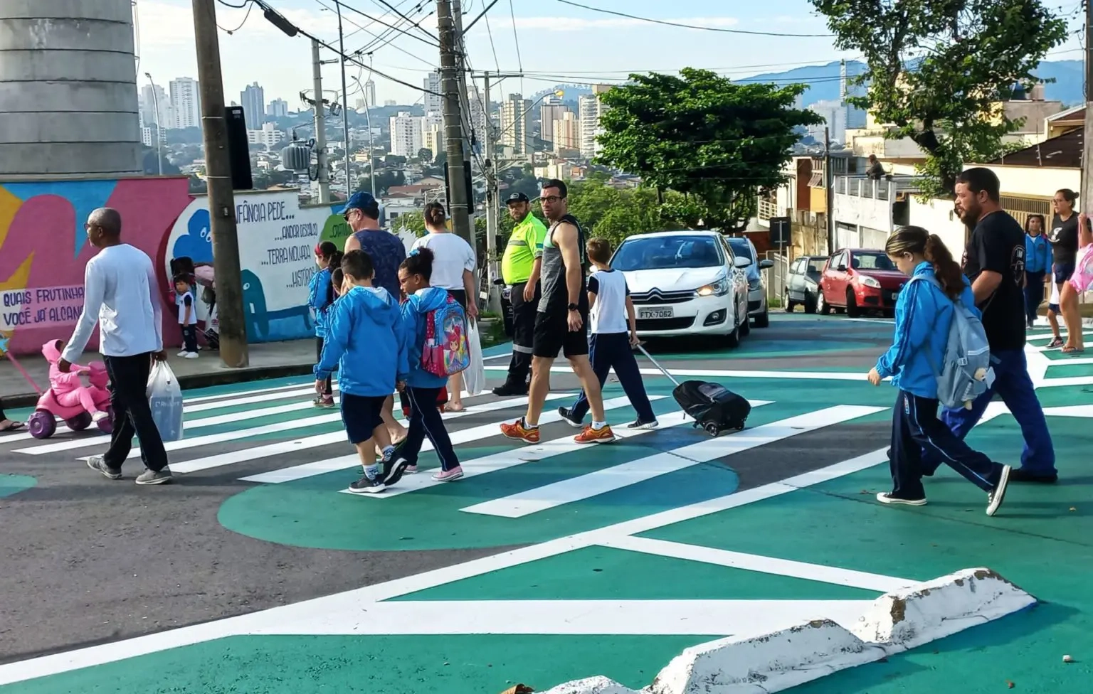 Pais e filhos atravessando a rua em rotina escolar.