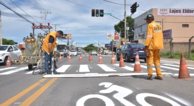 Trabalhadores do estado pintando faixas no asfalto das ruas de Aparecida.