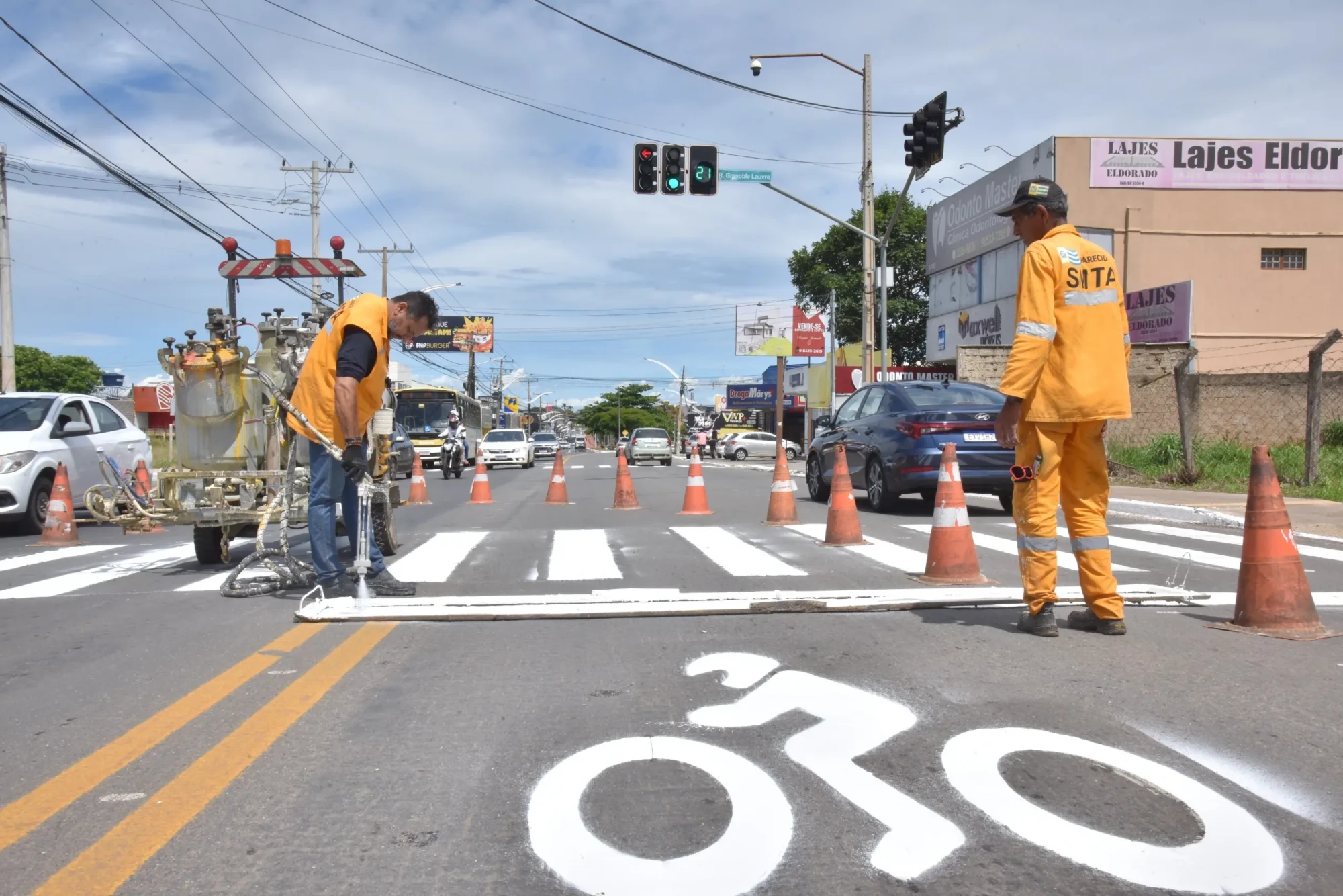 Trabalhadores do estado pintando faixas no asfalto das ruas de Aparecida.