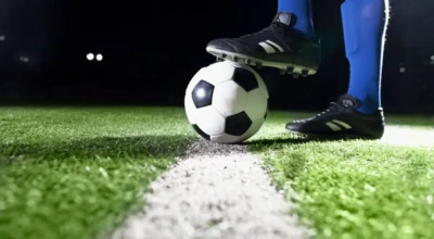 Jogador de futebol parado com o pé em cima da bola.